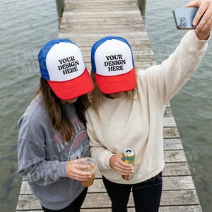 Otto Trucker Hat Mockup med två kvinnor på bryggan, röd vit blå keps livsstilsscen för Etsy och Print on Demand-butiker