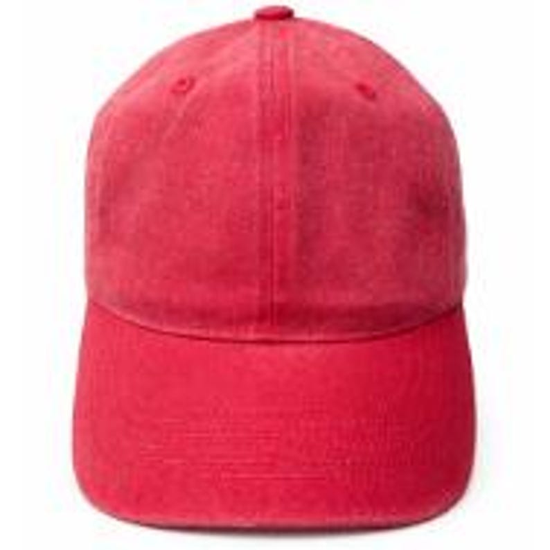 Puede incluir: Una gorra de b&eacute;isbol roja s&oacute;lida con construcci&oacute;n de seis paneles, visera curva y un bot&oacute;n cubierto de tela a juego en la corona. La tela tiene una textura ligeramente desgastada y lavada, y la gorra cuenta con ojales cosidos para ventilaci&oacute;n.