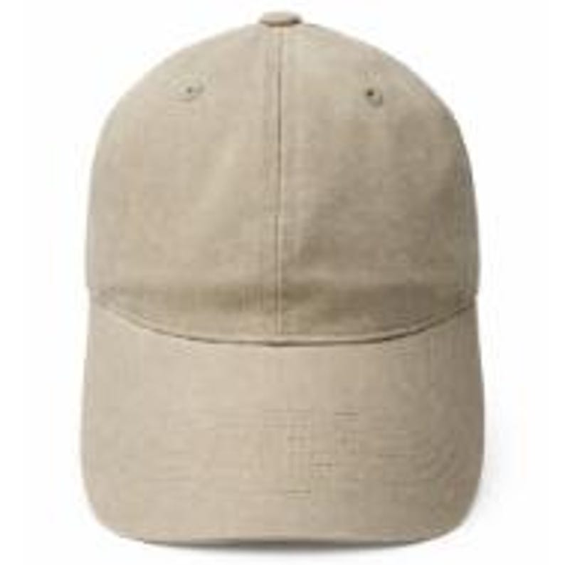 Puede incluir: Una gorra de b&eacute;isbol de color beige s&oacute;lido con una corona estructurada de seis paneles, una visera curva y un peque&ntilde;o bot&oacute;n en la parte superior central. La gorra presenta ojales cosidos en los paneles superiores y una textura uniforme.