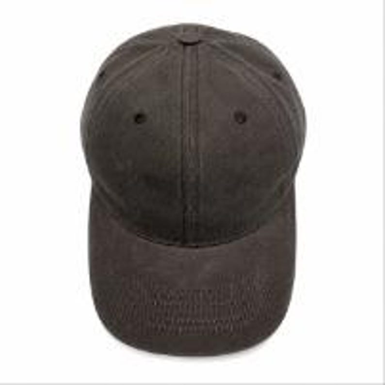 Puede incluir: Una gorra de b&eacute;isbol de color gris carb&oacute;n oscuro s&oacute;lido con una construcci&oacute;n de seis paneles, visera curva, un bot&oacute;n cubierto de tela en la corona y ojales cosidos para ventilaci&oacute;n, presentada desde una vista superior sobre un fondo liso.