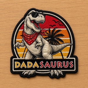 May include: Embroidered patch featuring a cartoon Tyrannosaurus Rex wearing sunglasses and a red bandana. The dinosaur is set against a sunset backdrop with a palm tree and the text "DADASAURUS" in a rectangular frame.