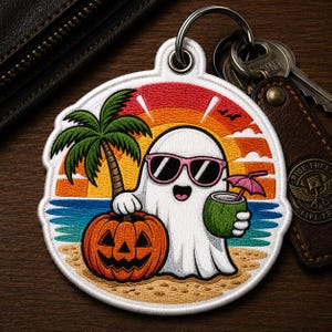 May include: A round keychain with a beach-themed design. It features a cartoon ghost wearing sunglasses, holding a coconut drink and standing next to a jack-o'-lantern. A palm tree, sunset, and ocean are in the background.