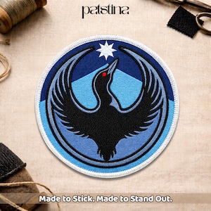 May include: Round patch featuring a stylized black bird with outstretched wings, a red eye, and a white star. The design is set against a blue and white background. The text "Made to Stick. Made to Stand Out." is at the bottom.