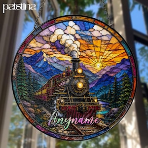 May include: Round stained glass window featuring a train traveling through a mountain landscape at sunset. The train is black and red, with the text "Anymame" in a cursive font. The window has a black border and is hanging from a chain.