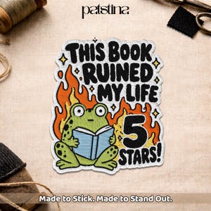 May include: Embroidered patch featuring a green frog reading a book, surrounded by flames. Text reads "THIS BOOK RUINED MY LIFE 5 STARS!" with the brand name "patstina" at the top. The patch is designed to stick and stand out.