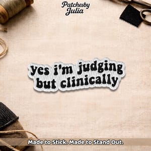 May include: A white and black embroidered patch with the text "yes I'm judging but clinically". The patch is on a beige fabric background. The text "Made to Stick. Made to Stand Out." is at the bottom.