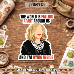 May include: A sticker with the text "THE WORLD IS FALLING APART AROUND US" and "AND I'M DYING INSIDE." The sticker features a blonde woman with red lipstick and a silver necklace. The sticker is on a wooden surface.