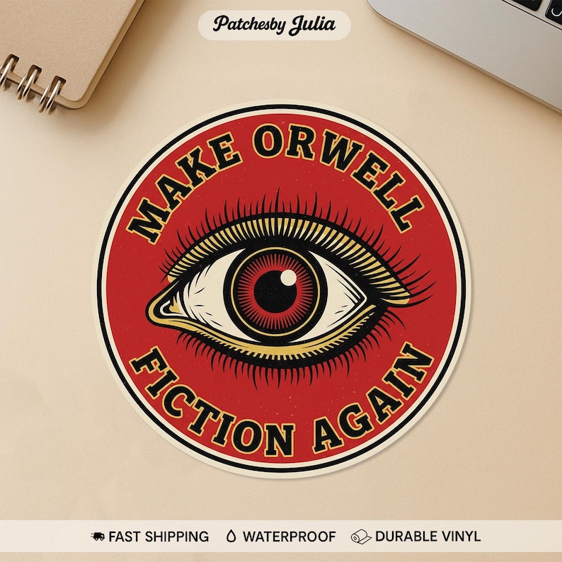 May include: A round sticker with a red background and the text "MAKE ORWELL FICTION AGAIN" in a gold, bold font. The sticker features a detailed eye graphic in the center with a red iris and gold accents. The sticker is waterproof and made of durable vinyl.
