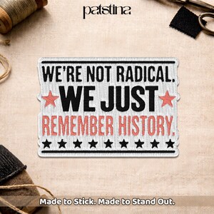 May include: Embroidered patch with the text "WE'RE NOT RADICAL. WE JUST REMEMBER HISTORY." in black and red. The patch has a white background with a black border and star accents. The patch is rectangular and reads "Made to Stick. Made to Stand Out."