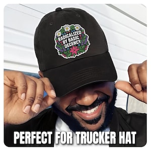 May include: Black baseball cap featuring a floral design and the text "RADICALIZED BY BASIC DECENCY". The cap has a curved peak and an adjustable strap. A classic style hat.