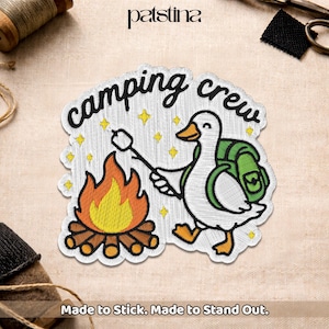 May include: Embroidered patch with a cartoon goose, backpack, campfire, and marshmallow. The patch reads "camping crew" in a whimsical font, with the text "Made to Stick. Made to Stand Out."