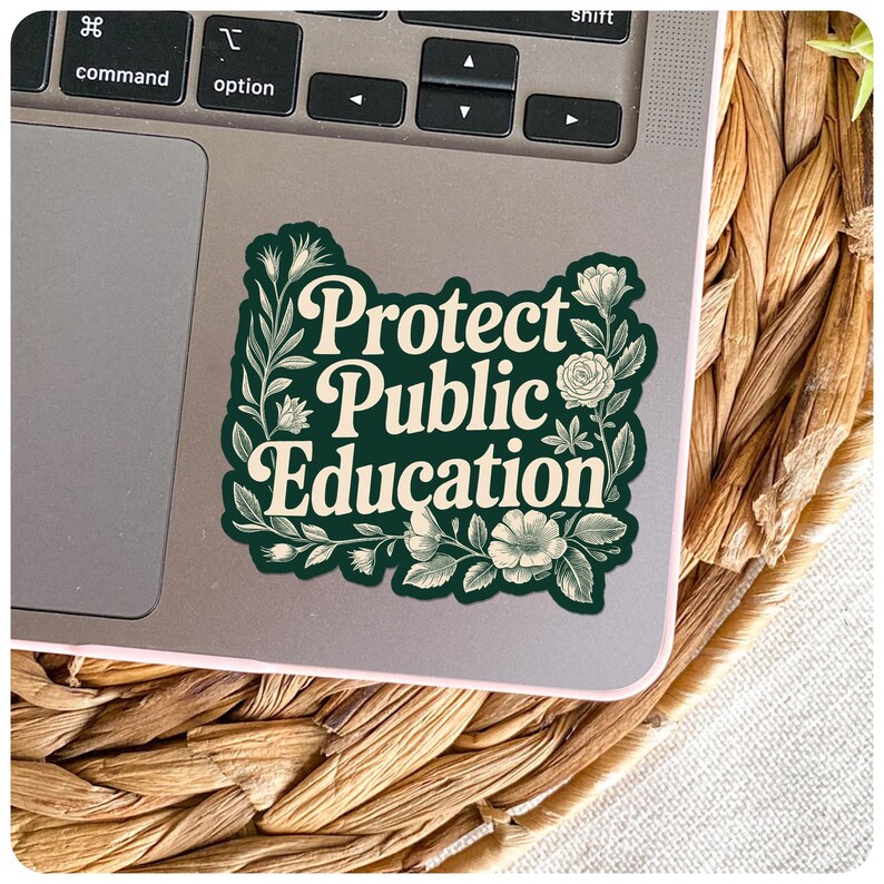 Peut inclure: Un autocollant avec le texte "Protect Public Education" en &eacute;criture blanche, entour&eacute; d'&eacute;l&eacute;ments floraux verts. L'autocollant est pos&eacute; sur un ordinateur portable, avec une texture tiss&eacute;e en arri&egrave;re-plan.