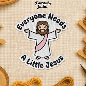 May include: Embroidered patch featuring a cartoon depiction of Jesus with outstretched arms, wearing a white robe and a pink sash. The patch has the text "Everyone Needs A Little Jesus" in a curved, white font. The brand name "Patchesby Julia" is at the top.