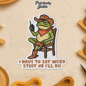 May include: Embroidered patch featuring a green frog wearing a cowboy hat, red bandana, and boots, seated in a chair and holding a walkie-talkie. The patch includes the text "I HAVE TO SAY WEIRD STUFF OR I'LL DIE".