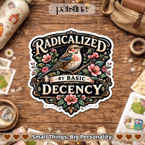 May include: A decorative sticker featuring a bird illustration, pink flowers, and the text "RADICALIZED BY BASIC DECENCY". The sticker has a black border and is set against a wooden background. The text "Small Things, Big Personality" is at the bottom.