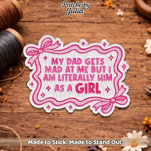 May include: Embroidered patch with the text "MY DAD GETS MAD AT ME BUT I AM LITERALLY HIM AS A GIRL" in pink and white. The patch has a pink border with bows and is on a wooden surface. The text "Made to Stick. Made to Stand Out." is at the bottom.