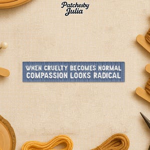 Peut inclure: Un écusson brodé bleu avec le texte "WHEN CRUELTY BECOMES NORMAL COMPASSION LOOKS RADICAL." L'écusson est entouré de fournitures de couture, dont du fil et une épingle.