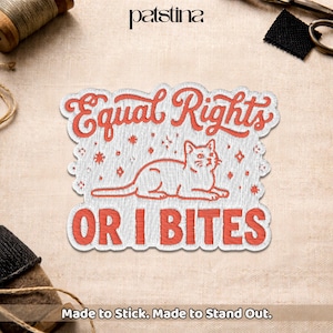 May include: Embroidered patch with the words "Equal Rights" and "OR I BITES" in red, featuring a cat illustration. The patch is white with red stitching and has a decorative border. The text "Made to Stick. Made to Stand Out." is at the bottom.
