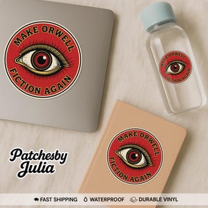May include: A sticker, water bottle, and notebook featuring a red and gold design with an eye and the text "MAKE ORWELL FICTION AGAIN." The water bottle has a light blue cap. The notebook is light brown. The sticker is on a laptop.
