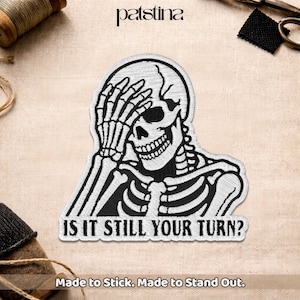 May include: Embroidered patch featuring a black and white skeleton covering its face with its hands. The text "IS IT STILL YOUR TURN?" is below the skeleton. The patch is designed to stick and stand out.