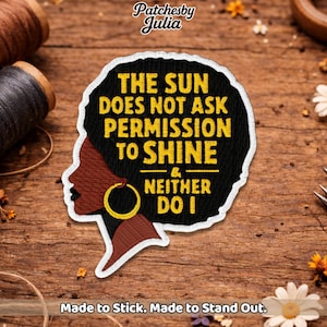 May include: Embroidered patch featuring a black woman's profile with a gold hoop earring. The patch has the text "THE SUN DOES NOT ASK PERMISSION TO SHINE & NEITHER DO I" in yellow. The patch is outlined in white and has the text "Made to Stick. Made to Stand Out."