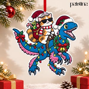 May include: A felt Christmas ornament featuring a blue dinosaur wearing a Santa hat and wrapped in colorful string lights, carrying a calico cat in sunglasses and a Santa hat with a gift sack. The text patstina is visible in the corner.