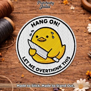 May include: Embroidered patch featuring a yellow cartoon chick holding a knife, with the text "HANG ON! LET ME OVERTHINK THIS." The patch has a white border and is on a wooden surface. The text "Made to Stick. Made to Stand Out." is at the bottom.