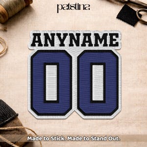 May include: Embroidered patch featuring the text "ANYNAME" above the number "00". The numbers are navy blue with a white border and black outline. The patch has the text "Made to Stick. Made to Stand Out."