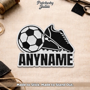 May include: Black and white embroidered patch with a soccer ball and a football boot. The patch has the word "ANYNAME" in white, block letters. The text "Made to Stick. Made to Stand Out." is at the bottom.