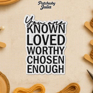 May include: A white and black embroidered patch with the words "You are KNOWN LOVED WORTHY CHOSEN ENOUGH". The patch has a white border and is on a beige fabric background. The brand name "Patchesby Julia" is at the top.