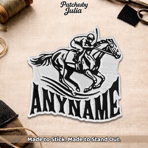 May include: Embroidered patch showing a black and white image of a jockey on a racehorse. The patch has the text "ANYNAME" in bold, black letters. The patch also includes the text "Made to Stick. Made to Stand Out."