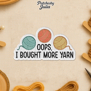 May include: A white patch with a cloud shape, featuring three yarn ball designs in teal, orange, and yellow. The text "OOPS. I BOUGHT MORE YARN" is printed below the yarn balls. The patch is likely for sewing or crafting.
