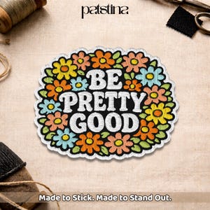 May include: Embroidered patch with a black background and the words "BE PRETTY GOOD" in white. The patch is surrounded by colorful embroidered flowers in shades of yellow, orange, and blue. The text "Made to Stick. Made to Stand Out." is at the bottom.