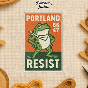 May include: Embroidered patch featuring a green frog wearing a white bandana, standing in front of an orange background. The patch reads "PORTLAND" above the frog, with "86" and "47" to the right. The word "RESIST" is at the bottom.