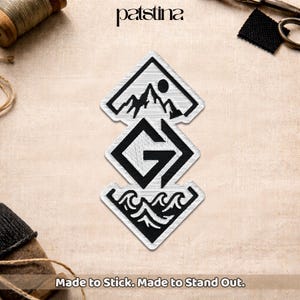 May include: Three embroidered patches with black and white designs. The top patch features a mountain scene with a sun, the middle patch has a letter "G", and the bottom patch shows ocean waves. The text "Made to Stick. Made to Stand Out."