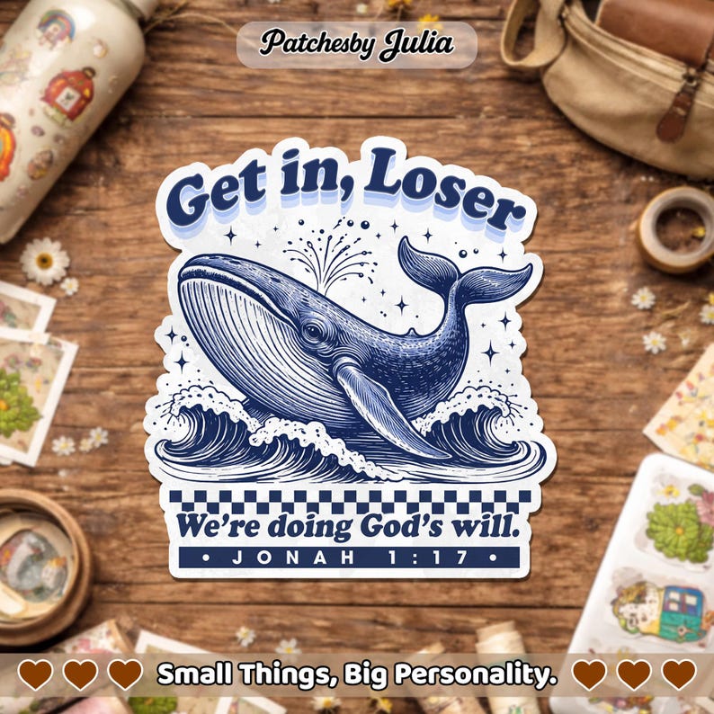 May include: A sticker featuring a blue whale breaching the ocean waves. The sticker has the text "Get in, Loser" above the whale and "We're doing God's will. Jonah 1:17" below. The sticker is on a wooden surface.