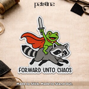 May include: Embroidered patch featuring a green frog with a red cape and a sword riding a gray raccoon. The patch has the text "FORWARD UNTO CHAOS" and "Made to Stick. Made to Stand Out."