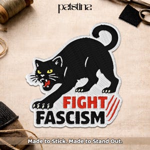 May include: Embroidered patch featuring a black panther with yellow eyes and an open mouth, above the words "FIGHT FASCISM" in red and white. The patch has a white border and the text "Made to Stick. Made to Stand Out."