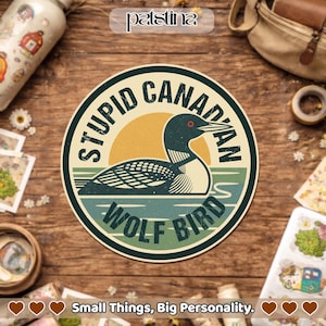 May include: A round sticker with a cartoon of a loon in a lake, with the words "STUPID CANADIAN WOLF BIRD" in a circular design. The sticker has a retro color scheme of teal, yellow, and cream.