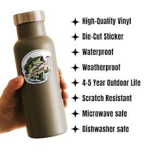 May include: A green insulated water bottle with a sticker featuring a fish jumping out of the water. The sticker has the text "ANYNAME". The bottle is held by a hand. The image also includes text: High-Quality Vinyl, Die-Cut Sticker, Waterproof, Weatherproof, 4-5 Year Outdoor Life, Scratch Resistant, Microwave safe, Dishwasher safe.