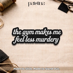 May include: Black embroidered patch with the text "the gym makes me feel less murdery" in white script. The patch has a white border and is set against a neutral background. The brand name "patstina" is at the top.