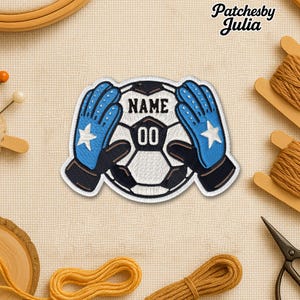 May include: Embroidered patch featuring a soccer ball held by blue gloves with white stars. The patch has the text "NAME" above the number "00". The patch is white with black and blue accents. The patch is made by Patchesby Julia.