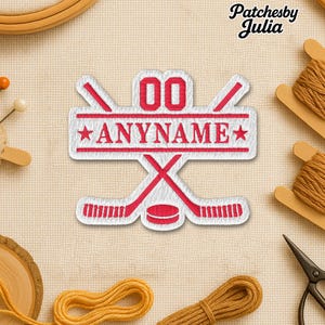 May include: Embroidered patch with a hockey theme. The patch is white with red accents, featuring crossed hockey sticks, a puck, and the text "00" above "ANYNAME". Two stars flank the text. The patch is surrounded by sewing supplies.