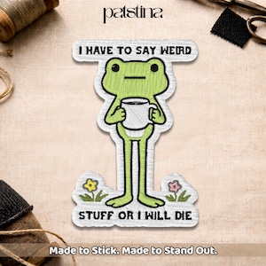 May include: Embroidered patch featuring a green frog holding a mug, with the text "I HAVE TO SAY WEIRD STUFF OR I WILL DIE." The patch has a white border and is decorated with small flowers. The brand name "patstina" is at the top.