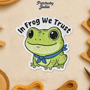 May include: Embroidered patch featuring a smiling green frog with large black eyes and a blue neckerchief. The patch has the text "In Frog We Trust" in white, arched above the frog. The patch is on a beige fabric background.
