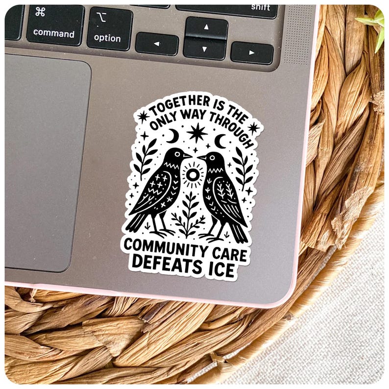 May include: A black and white sticker featuring two birds facing each other, with the text "TOGETHER IS THE ONLY WAY THROUGH" and "COMMUNITY CARE DEFEATS ICE". The sticker is on a laptop.