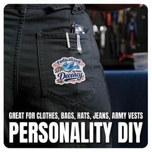 K&ouml;nnte beinhalten: Schwarze Jeanshose mit einem Aufn&auml;her "radicalized by basic Decency", der einen blauen Vogel mit einer Blume zeigt. Der Text "GREAT FOR CLOTHES, BAGS, HATS, JEANS, ARMY VESTS PERSONALITY DIY" ist ebenfalls enthalten.