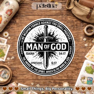 May include: A round, black and white sticker with the text "MAN OF GOD" and a sword graphic. The sticker includes Bible verses and the phrase "NO WEAPON FORMED AGAINST YOU SHALL PROSPER". The sticker is on a wooden surface.