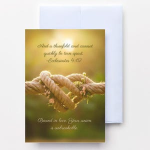 May include: A greeting card with a photograph of a knotted rope adorned with small pink flowers. The card features the text "And a threefold cord cannot quickly be torn apart. -Ecclesiastes 4:12" and "Bound in love. Your union is unbreakable."