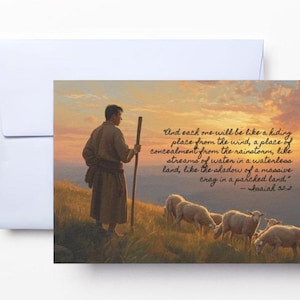May include: A greeting card featuring a painting of a shepherd and sheep on a hillside at sunset. The card includes a quote from Isaiah 32:2 in script. The card is inside a white envelope.